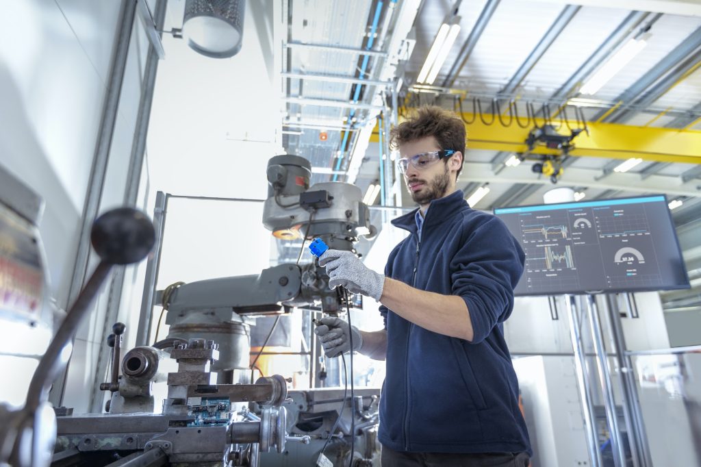 Robotics engineer fitting sensors to traditional engineering lathe in robotics research facility